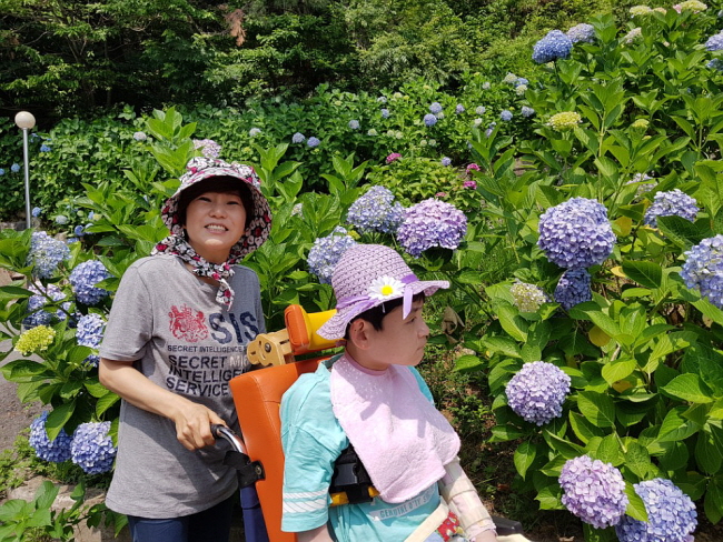 거주인의 모자에 달린 꽃과 수국꽃. 주변이 온통 꽃밭이네요! 조명순 님과 함께 활짝 웃으며 사진 찍었습니다