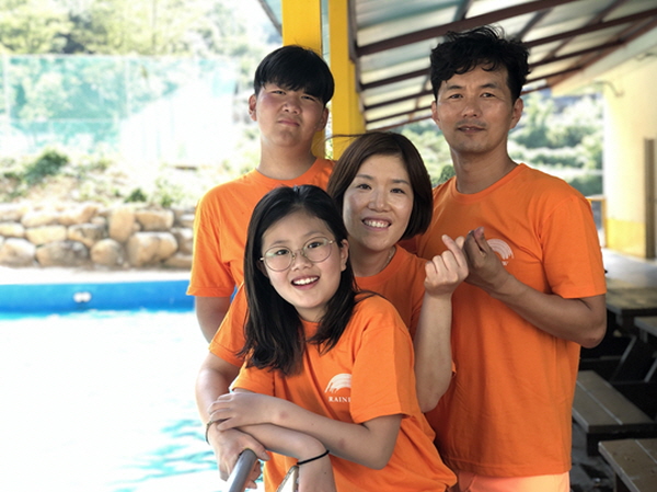 주황색 티를 맞춰 입은 따뜻한 가족사진