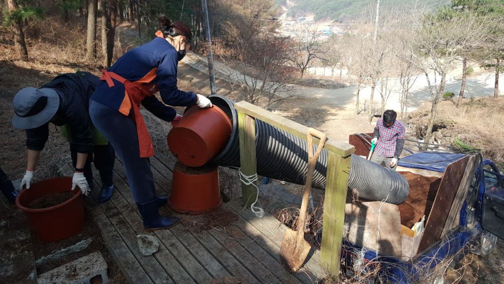  파이프 통에 똥 퇴비를 붓고 있는 행자들