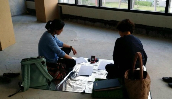 불사가 진행 중인 법당에서 휴대폰으로 법문을 들으며 열공하는 도반들