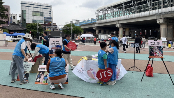 JTS 홍보 패널과 플래카드 설치하는 봉사자들과 아이들